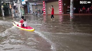 Bambini fanno surf in una strada allagata in Vietnam