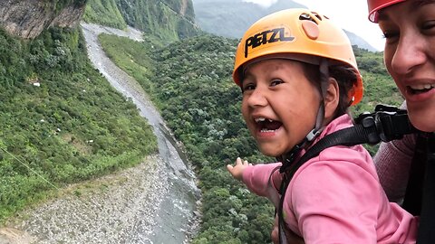 Child giggles with delight as she sails over a waterfall in Ecuador