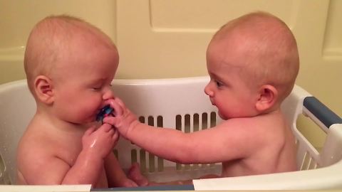 Twin Baby Boys Exchange A Pacifier From Each Other In A Bathtub
