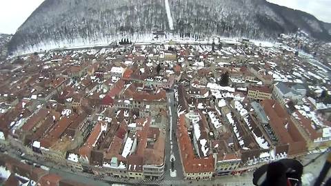 Paragliding above a snow-covered city in Transylvania