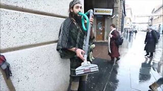Artista di strada suona con il tubo dell'aspirapolvere