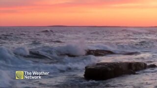Waves roll onto shore during a magenta sunset