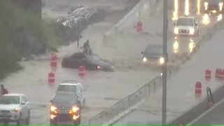 Woman stranded on top of flooded car