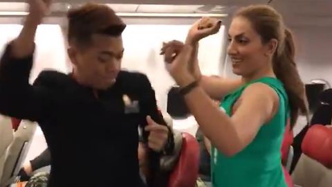 Cabin crew and passengers dance in airplane