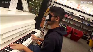 Un jeune homme joue du piano les yeux bandés