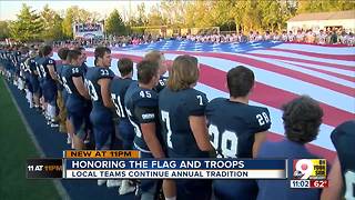 Rival high school teams hold giant U.S. flag together