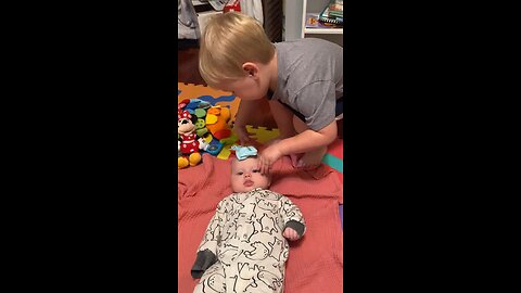 Toddler Puts a Bow on Baby Sister