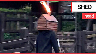 Just a man walking along the street with a flame-throwing shed on his head
