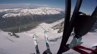 Sciatore salta da una montagna e vola in paracadute