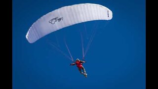 Atleta executa múltiplas manobras voando de parapente