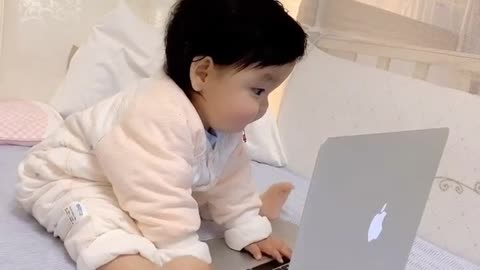 a cute little baby play with laptop moving his feet