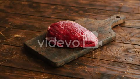 Big fresh piece of meat laid on wooden cutting board