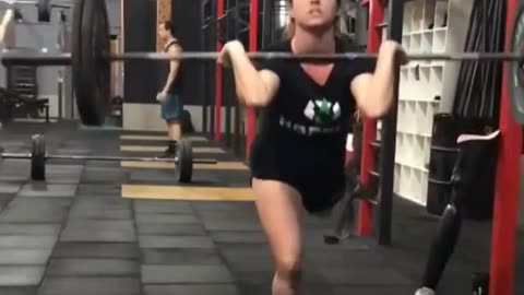 A girl lifts a barbell on one leg