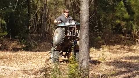 Guy does a wheelie on an atv and falls off before hitting tree