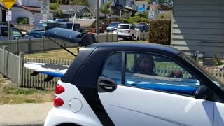 Smart car with surf board in the back of car