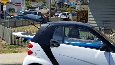 Smart car with surf board in the back of car