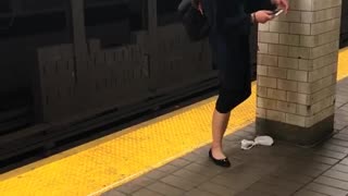 Woman puts foot above head and texts on subway platform