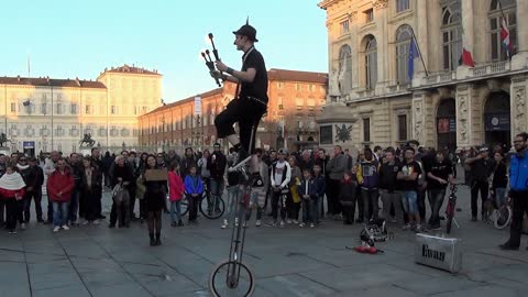 Street performer juggles torches while balancing on a unicycle