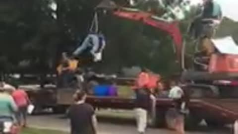 Guy strapped to excavator tosses candy during parade