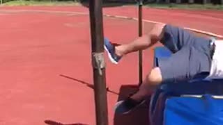 Guyrunning on track field tries to jump over pole fails
