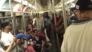 Guy white tank top black shorts upside down dancing on subway train pole