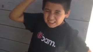 Little kid in black bam shirt keeps hitting himself in head with fist