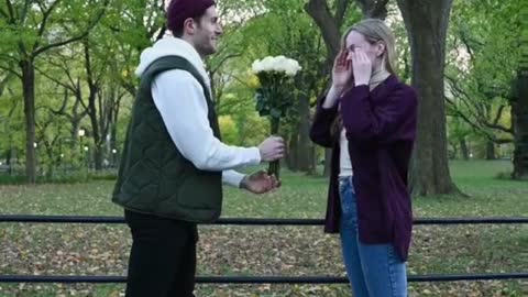 Boy surprise girl with beautifull flowers in park