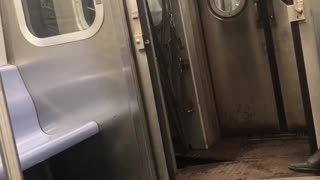 Man black jacket holding subway doors open while train moves