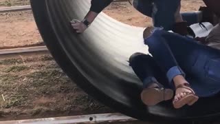 Two girls rolling in a black tube girl in red falls over
