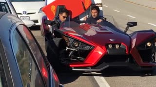 Guy in red car backing up with two surfboards in back