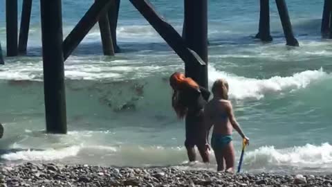 Woman with red hair dancing on beach filmed buy her friend