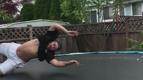 Guy tries to backflip in trampoline and lands on head, holds head in shame