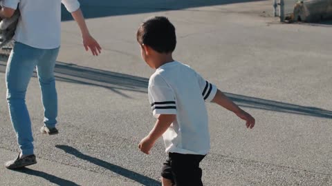 Cute boy chasing his dad while carrying a cute dog