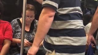 Guy grey and blue striped shirt polo falling asleep standing up holding onto pole subway train