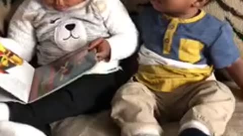 Big sister reads baby brother a story