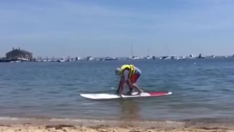 Guy yellow life vest paddleboard falls face first water