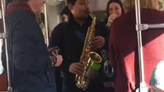 Guy playing saxophone on subway train