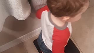 A 23-month-old boy steps on the scale, not happy with the holiday weight