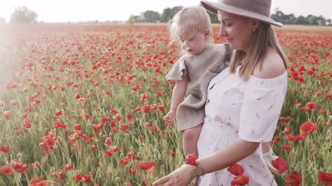 Woman Walking on Red Poppy Flower Field While Carrying Her Baby