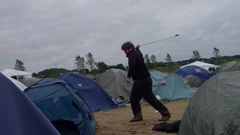 Guy hits blue tent with golf club