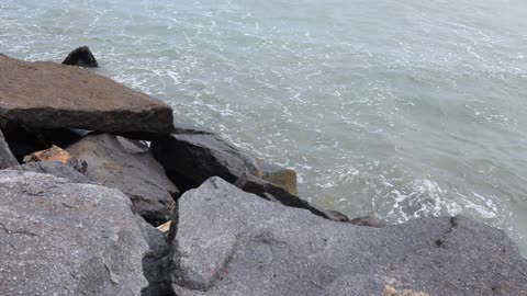 Waves crashing on breakwater rocks