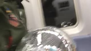 Guy holds giant disco ball on subway train