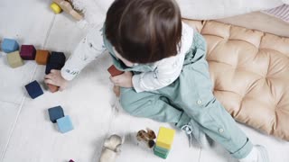 A Little Kid Is Playing With Color Coded Wooden Blocks