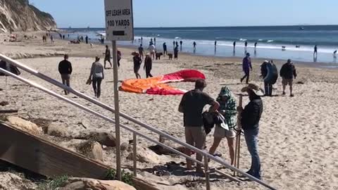Orange parachute guy tries to run across beach