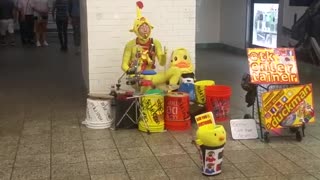 Man in yellow outfit plays drums in subway station