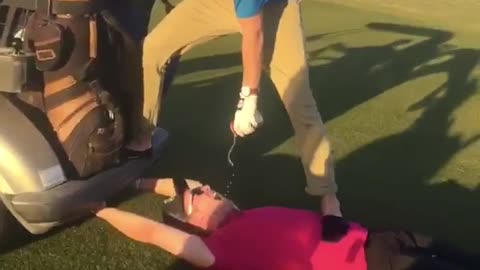 Guy pours beer in mouth of friend on golf course