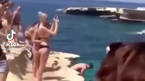 Funny crazy dog jumps from cliff in water