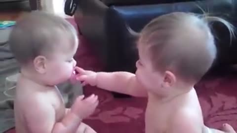 Cute babies taking turns stealing the pacifier for each other