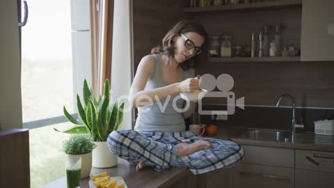 Attractive woman sitting on table and eating breakfast