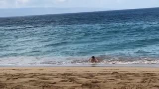 Guy in blue shorts on skimboard in water